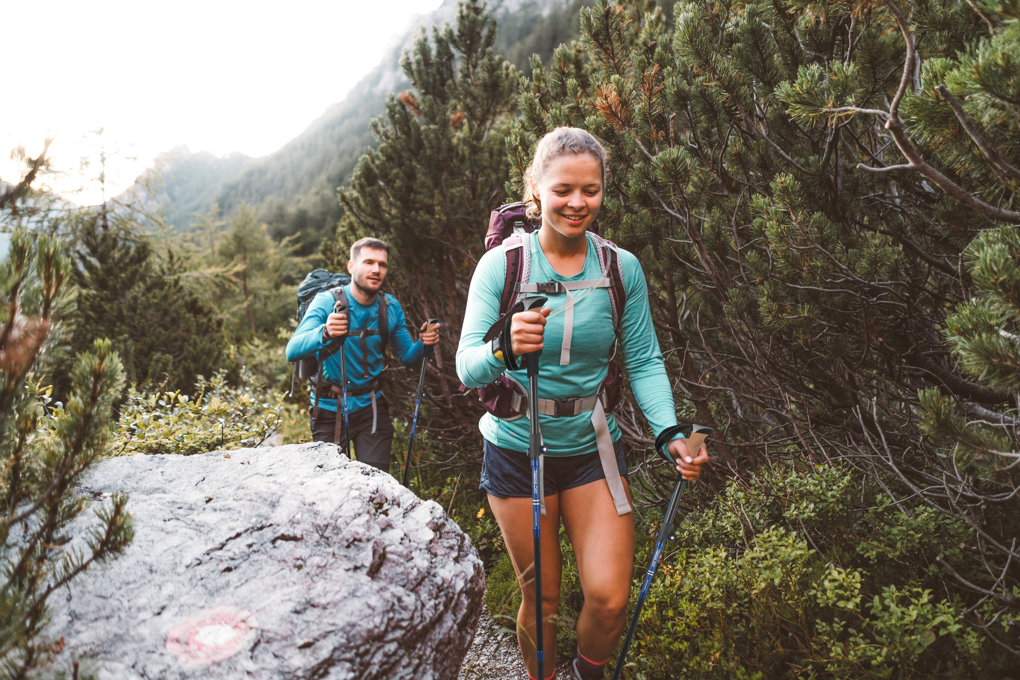 Two hikers on a trail with mountains in the background