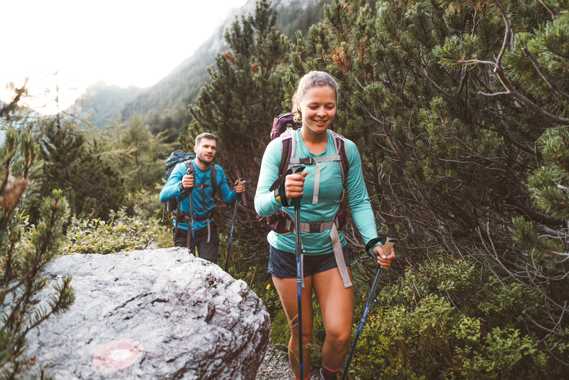 Two hikers on a trail with mountains in the background